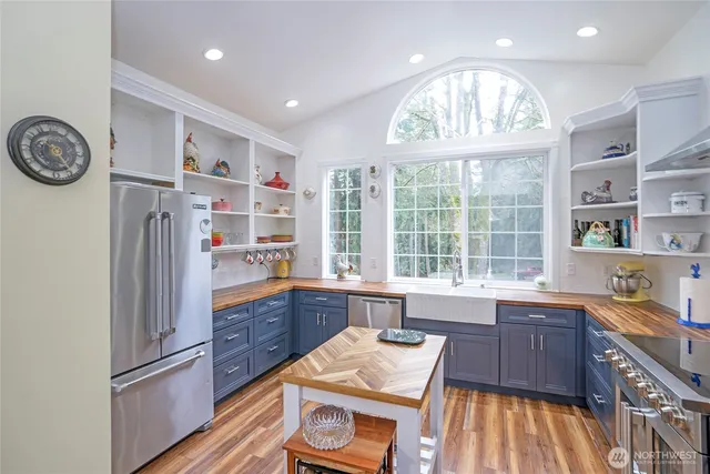 a kitchen with stainless steel appliances granite countertop a refrigerator a sink dishwasher a stove and a dining table with wooden floor