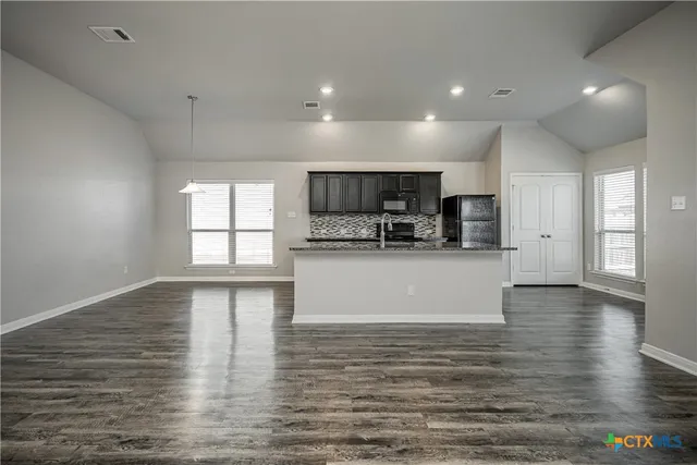 a view of kitchen with microwave a refrigerator and cabinets