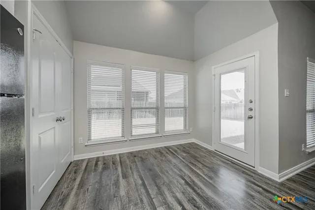 a view of an empty room with glass door and wooden floor