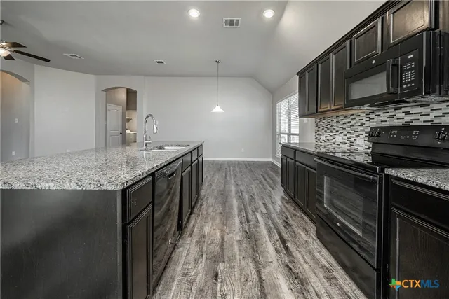 a kitchen with stainless steel appliances granite countertop a kitchen island hardwood floor sink and stove