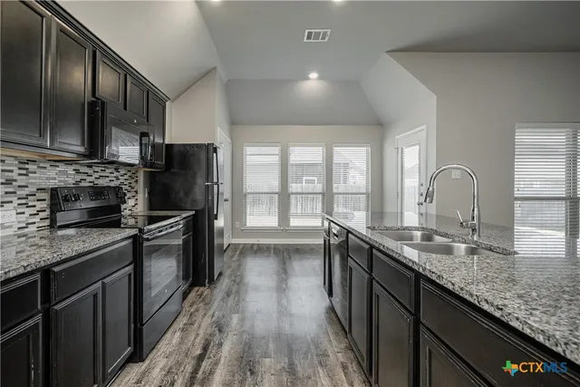 a kitchen with stainless steel appliances granite countertop a sink stove and refrigerator