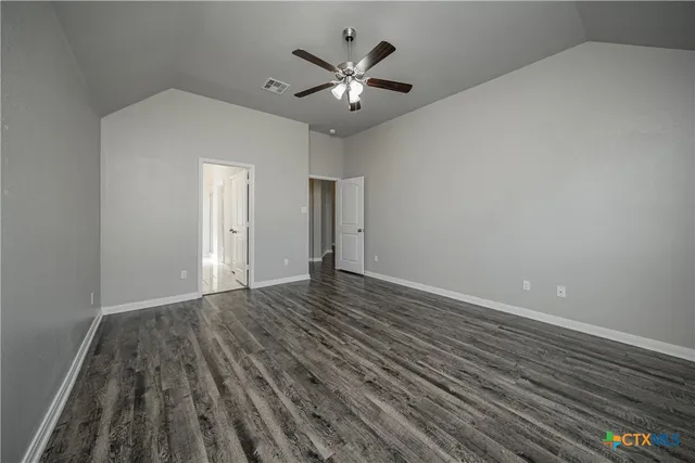 a view of an empty room with chandelier fan and wooden floor