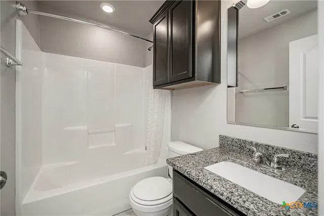 a bathroom with a granite countertop sink a toilet and shower