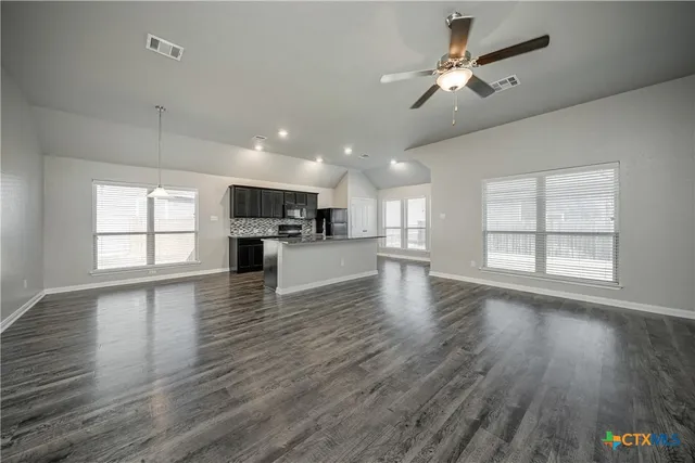 a view of a kitchen with furniture a ceiling fan and wooden floor