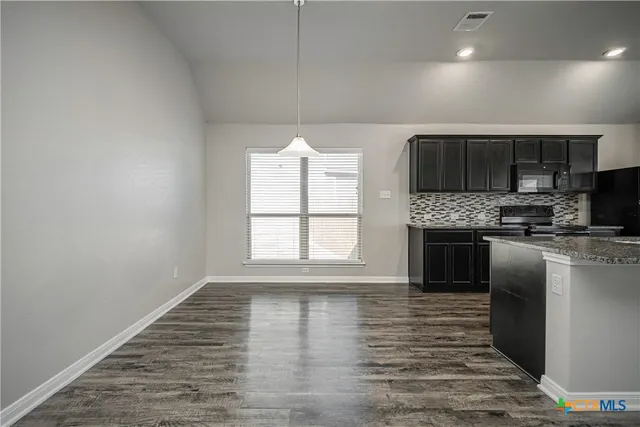 a kitchen with granite countertop a stove a sink and a microwave