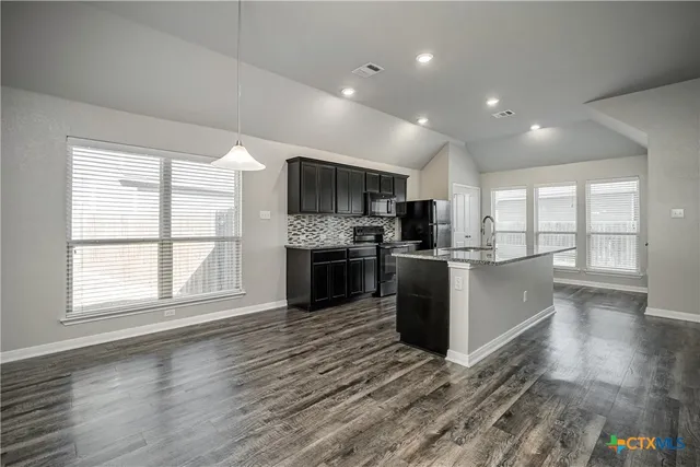 a large kitchen with a large counter top stainless steel appliances and cabinets