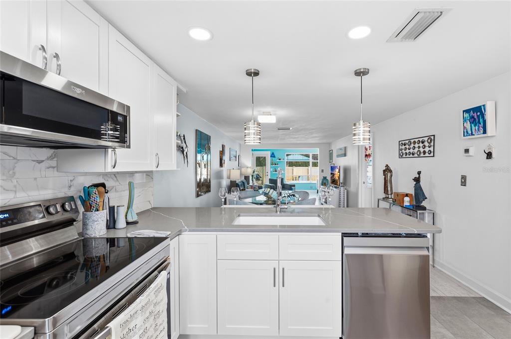 4467 Rustic Drive New Port Richey, FL 34652 - Photo 8 of 44 a kitchen with stainless steel appliances granite countertop a sink a stove top oven a chimney and cabinets