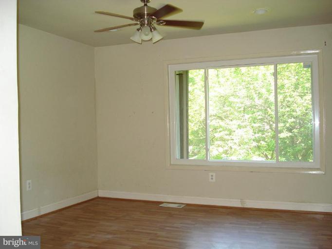 9072 Centerway Road Gaithersburg, MD 20879 - Photo 9 of 15 an empty room with wooden floor fan and windows