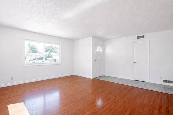 an empty room with wooden floor and window