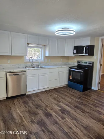 a kitchen with stainless steel appliances granite countertop a stove top oven a sink dishwasher and a refrigerator