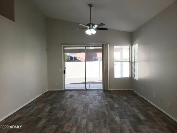 an empty room with chandelier fan and windows