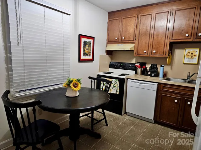 a kitchen with stainless steel appliances granite countertop a stove top oven a refrigerator a dining table and chairs with wooden floor