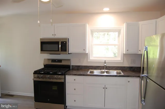 a kitchen with granite countertop a sink stainless steel appliances and window