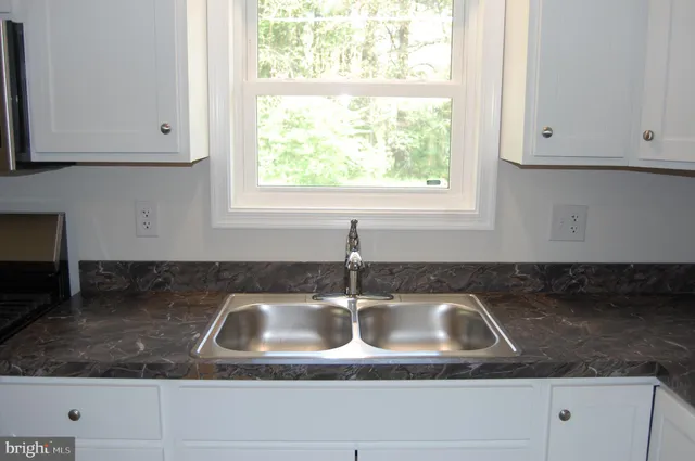 a kitchen with granite countertop white cabinets and a sink
