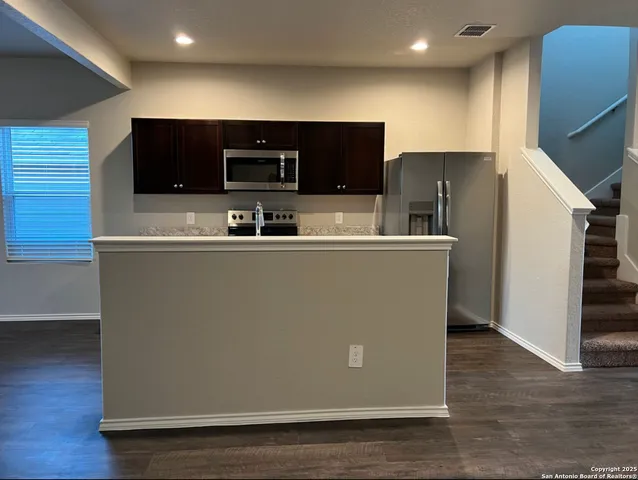 a view of a kitchen with stainless steel appliances wooden floor and chair