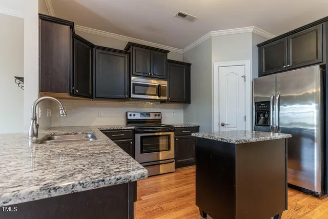 a kitchen with kitchen island granite countertop a sink stove and refrigerator