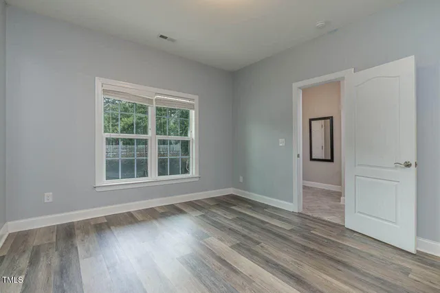 a view of an empty room with wooden floor and a window