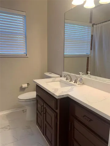 a bathroom with a granite countertop sink and a toilet