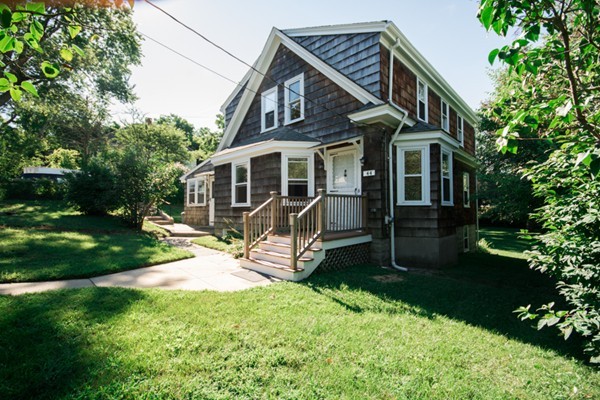 a view of a house with a yard and a wooden bench