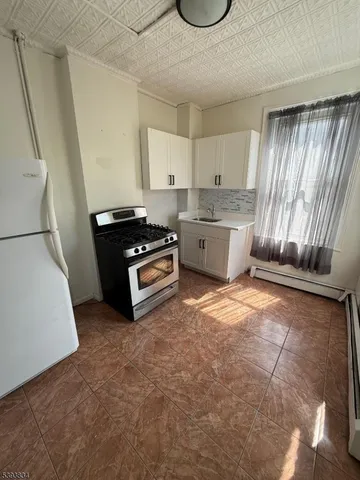 a kitchen with granite countertop a stove a sink and a refrigerator