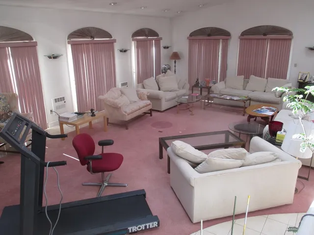 a living room with couches chairs and large windows with wooden floor