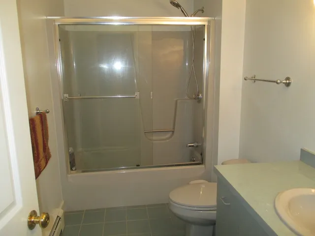 a bathroom with a granite countertop bathtub shower sink vanity and toilet