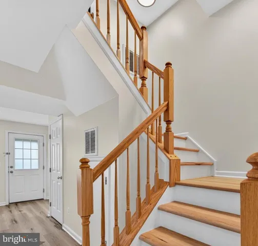 a view of staircase with lots of frames on wall and wooden floor