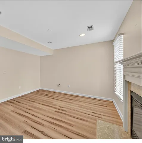 a view of empty room with fireplace and wooden floor