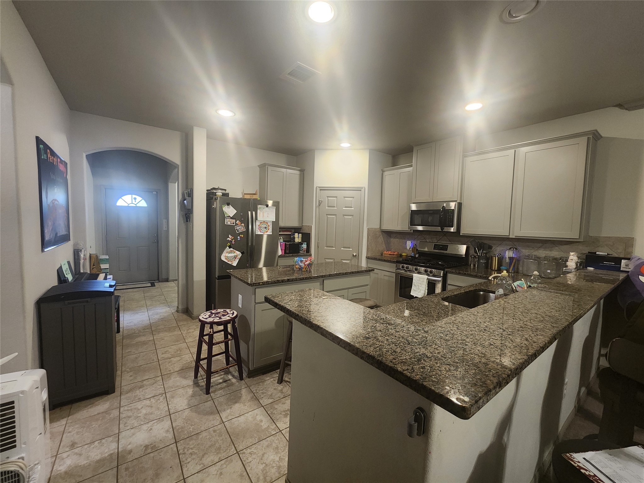 15611 Jackie Robinson Road Splendora, TX 77372 - Photo 3 of 6 Photo showcases a modern kitchen with stainless steel appliances, island in center of kitchen and ample cabinetry. The space features recessed lighting and a tiled floor, creating a bright and functional area for cooking and entertaining.