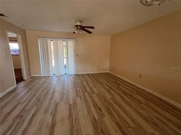 a view of a room with wooden floor ceiling fan and windows