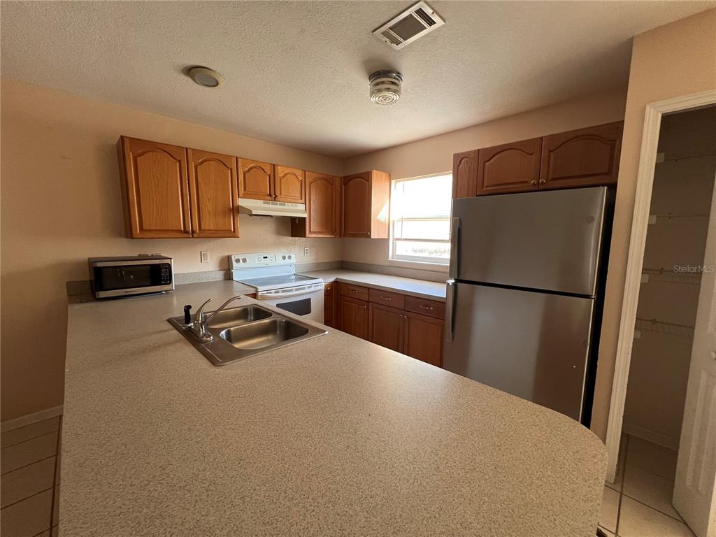 27082 Adams Street, Unit A Punta Gorda, FL 33983 - Photo 3 of 8 a kitchen with sink refrigerator and cabinets