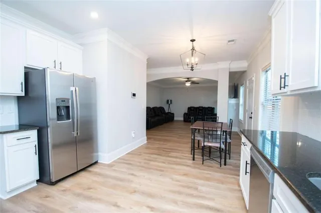 a dining room with kitchen island stainless steel appliances furniture a chandelier and a kitchen view