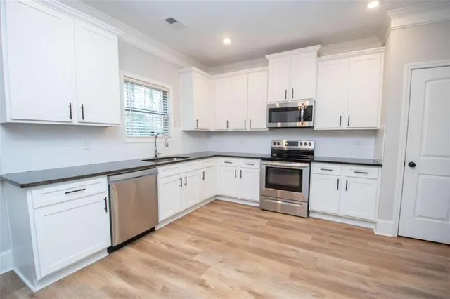 a kitchen with granite countertop white cabinets and white appliances