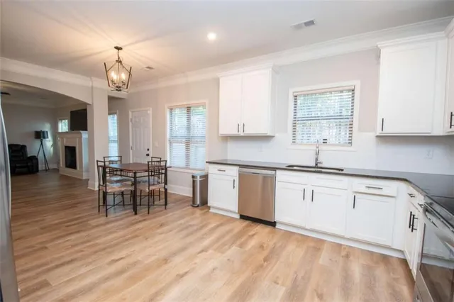 a kitchen with granite countertop a stove a sink a dining table and chairs