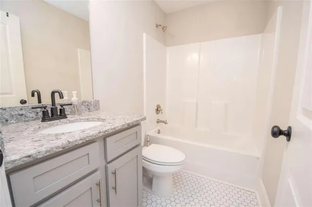 a bathroom with a granite countertop sink a toilet and shower