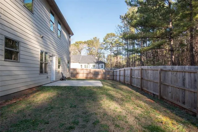a view of a backyard with wooden fence and large trees