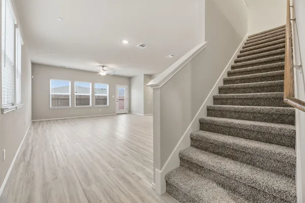a view of an empty room with wooden floor and windows