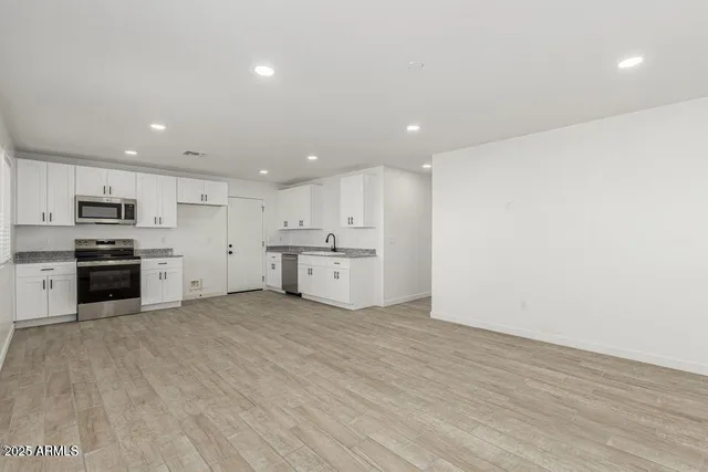 a large kitchen with stainless steel appliances granite countertop a stove a sink and a refrigerator