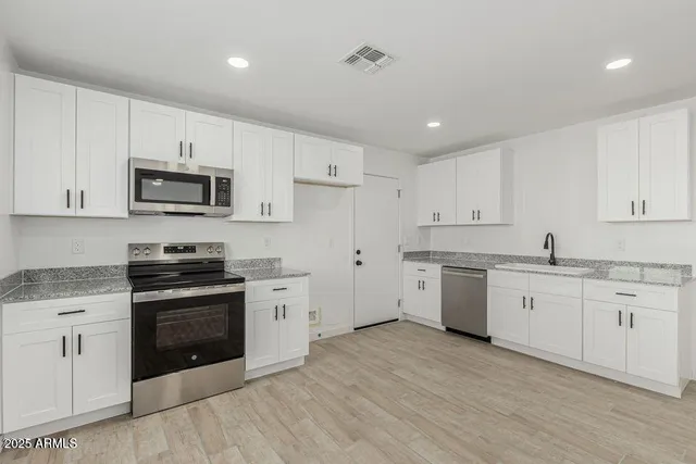 a kitchen with granite countertop white cabinets and stainless steel appliances