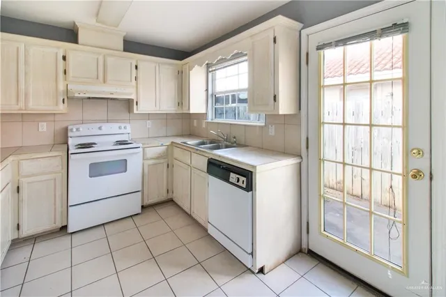 a white kitchen with a stove top oven sink and window