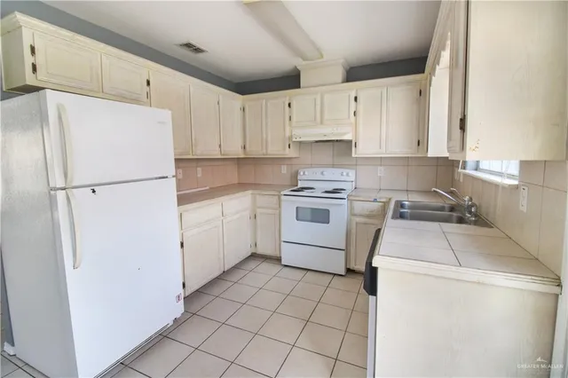 a kitchen with a refrigerator sink stove and cabinets