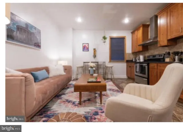 a living room with furniture a wooden floor and kitchen view