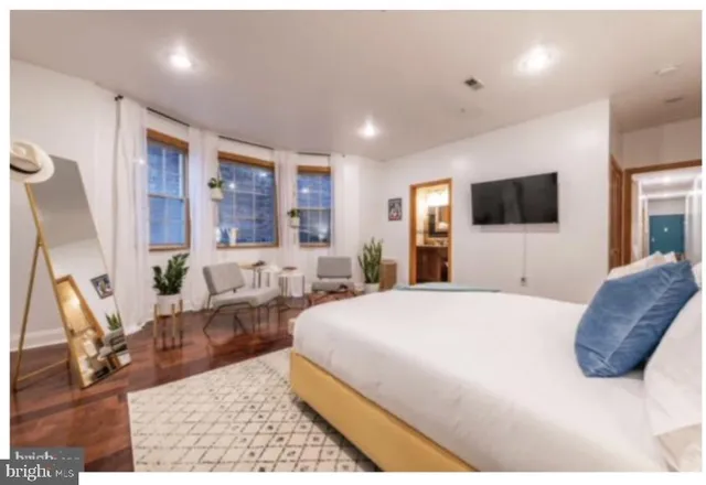 a bedroom with a large bed and a flat tv screen on dresser