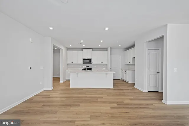 a kitchen with stainless steel appliances granite countertop a sink a stove a refrigerator and white cabinets