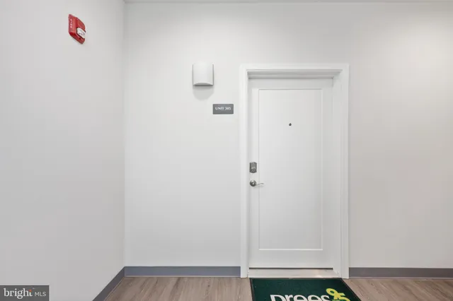 a view of an empty room with wooden floor and windows