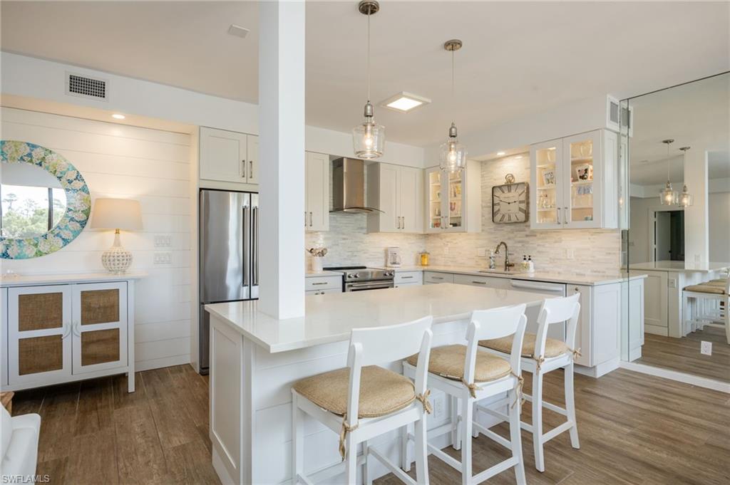 312 Bears Paw Trail Naples, FL 34105 - Photo 4 of 34 a kitchen with stainless steel appliances granite countertop a stove top oven a refrigerator a sink and a dining table with wooden floor