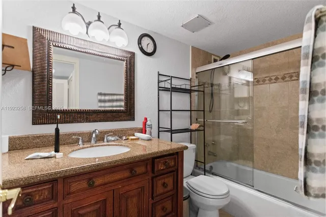 a bathroom with a granite countertop sink toilet a mirror and shower