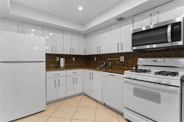 a kitchen with stainless steel appliances granite countertop white cabinets sink and a granite counter top