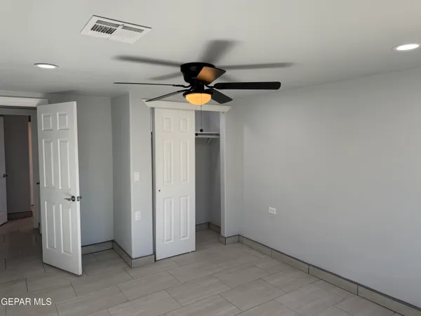 an empty room with windows and a ceiling fan
