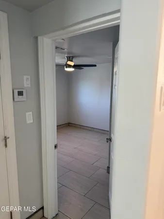 an empty room with a chandelier fan and wooden floor
